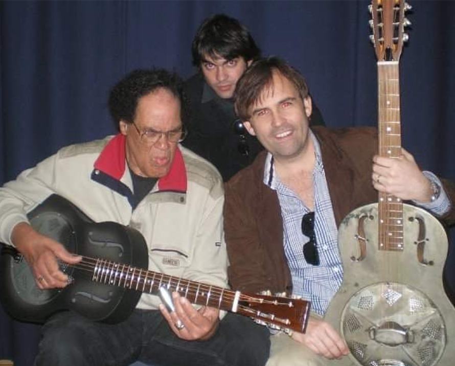 Marco Farris backstage with two musicians holding resonator guitars