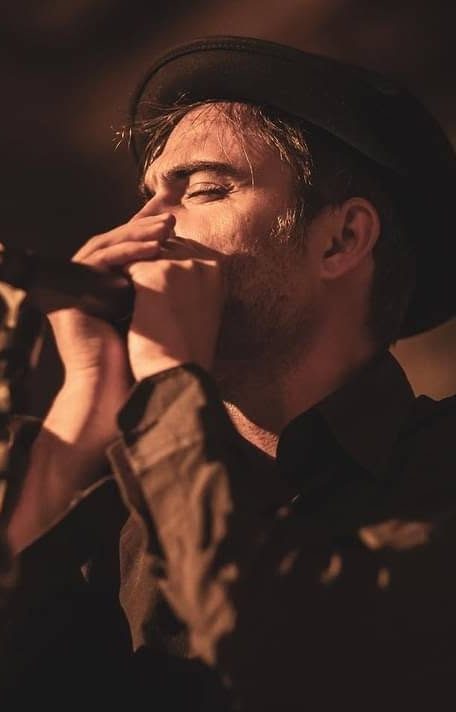 Marco Farris playing harmonica into a microphone