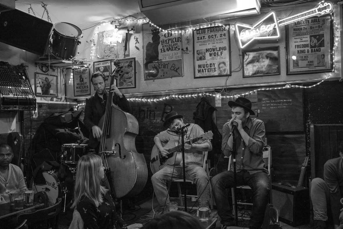 Marco Farris on harmonica with a double bass and guitar trio at Ain't Nothin' But The Blues